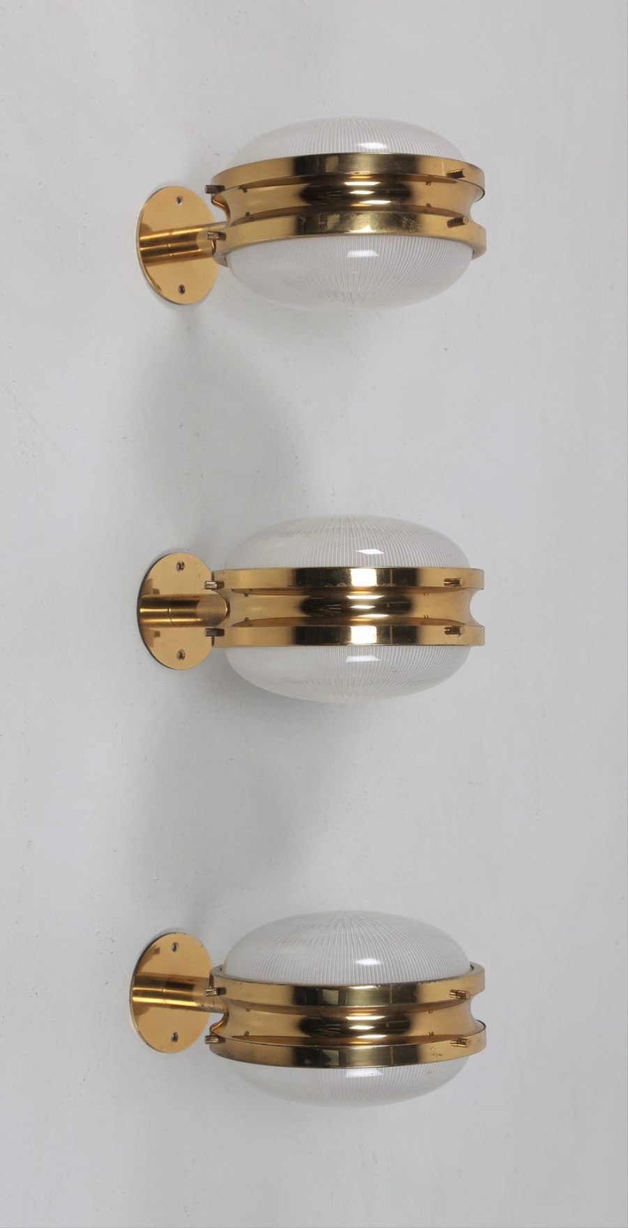 Tre lampade da parete in ottone e cristallo pressato, mod. Gamma/C per ARTEMIDE, 1960.
Pubblicazioni; Domus num. 366 maggio 1960 pag. 46; Catalogo Artemide 1969.
 (Sergio Mazza)