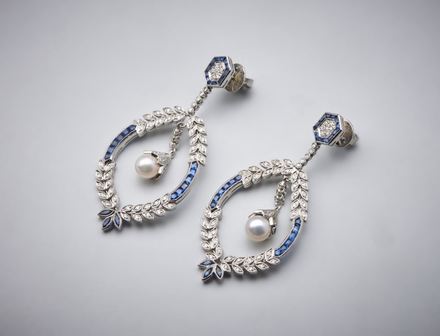 Un paio di orecchini "Liberty" pendenti in oro bianco 750/1000 con zaffiri blu carrè, diamanti bianchi  taglio huit huit e perle sferiche.  (. )
