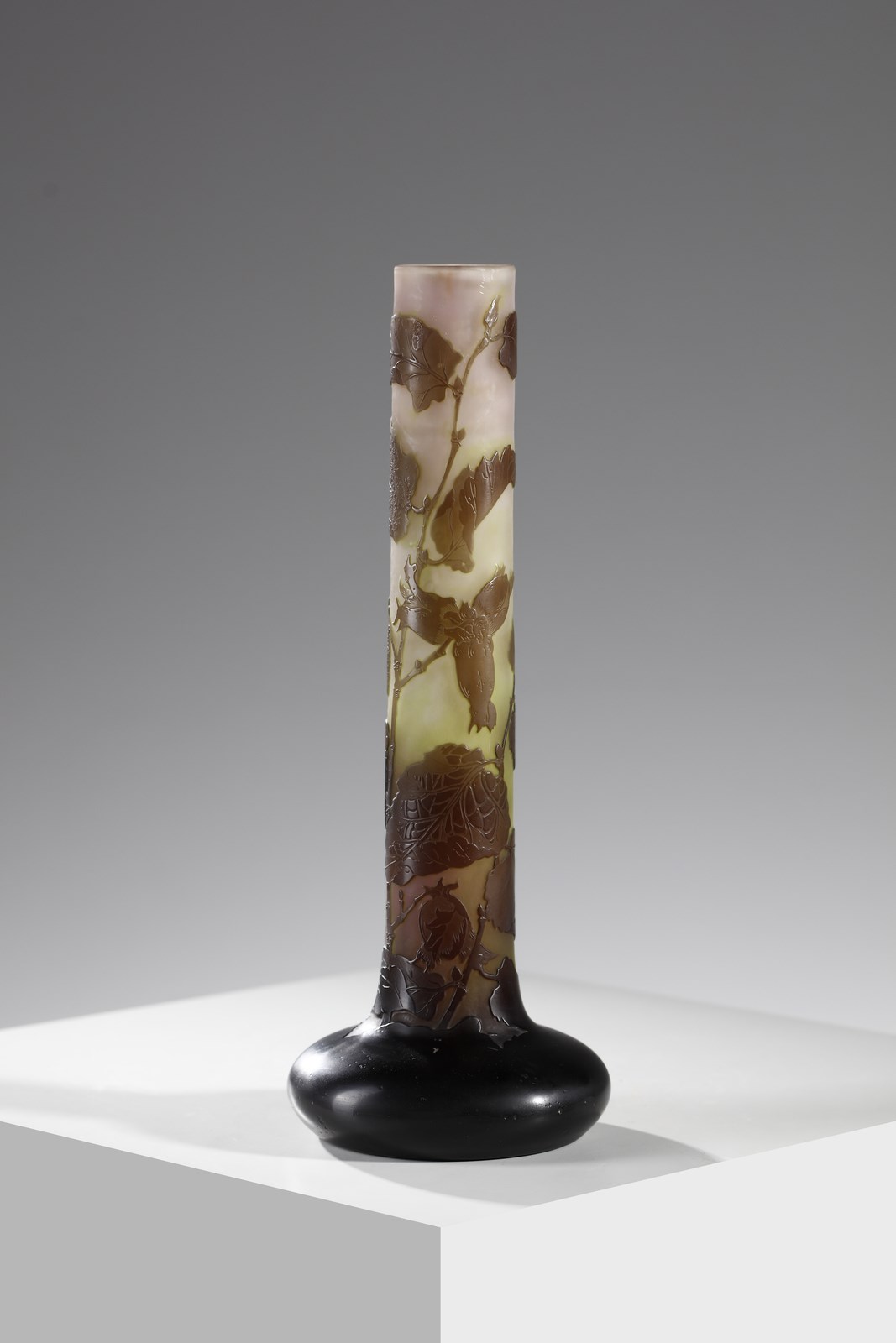 Vaso cilindrico con base a bulbo in vetro doppio, decoro di foglie nei toni del bruno, finemente inciso ad acido su fondo variegato verde e rosato ( Gallé)