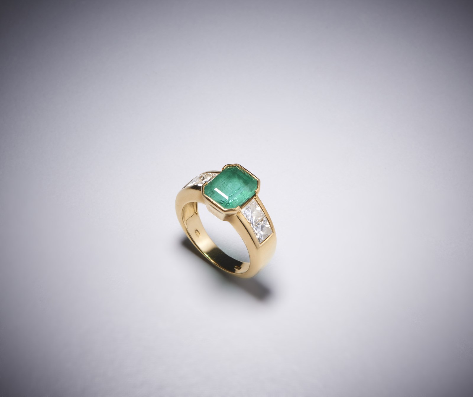 Un anello in oro giallo 750/1000 con smeraldo colombiano centrale ct 2,50 con contorno di diamanti bianchi  taglio princess, 1,30 ct.circa. (. )