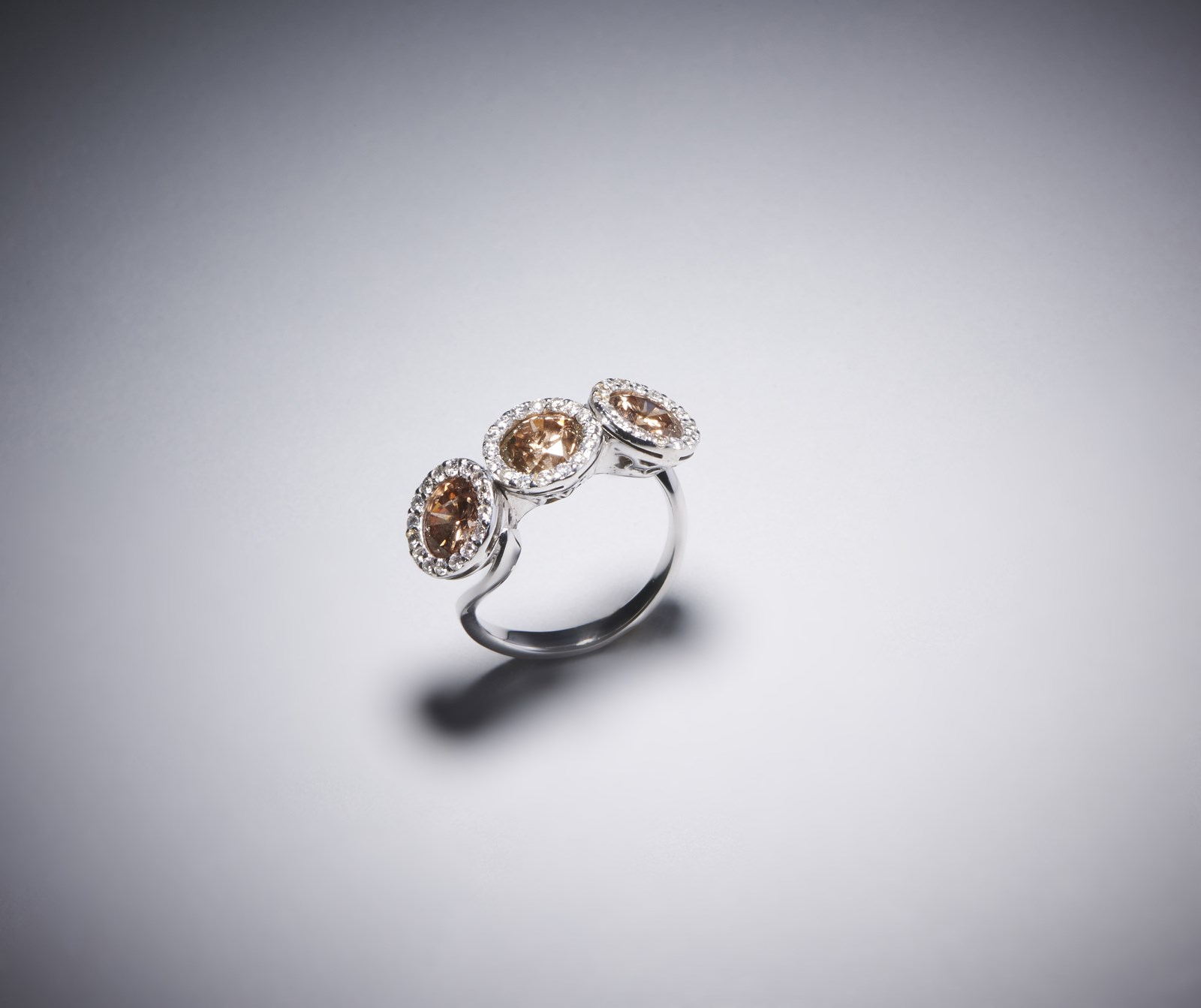 Anello in oro bianco 750/1000 con tre diamanti brown taglio a brillante per 4,00 ct. totali circa e pavè di diamanti bianchi  taglio misto di circa 1,30 ct. (. )