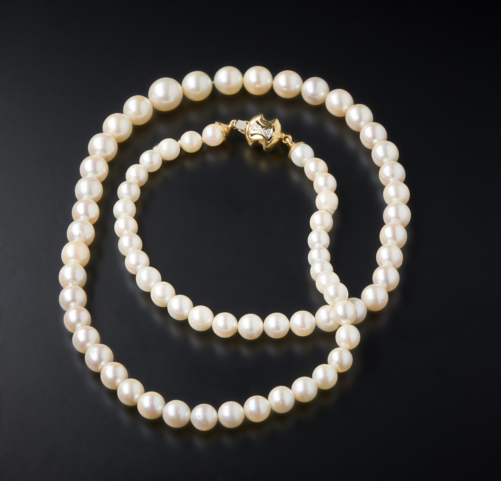 7 mm spherical white cultured pearl wire with 750/1000 yellow gold clasp and small diamonds. (. )