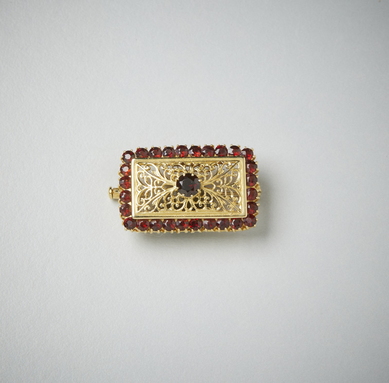Yellow gold brooch 750/1000 perforated with orange garnets.  (. )
