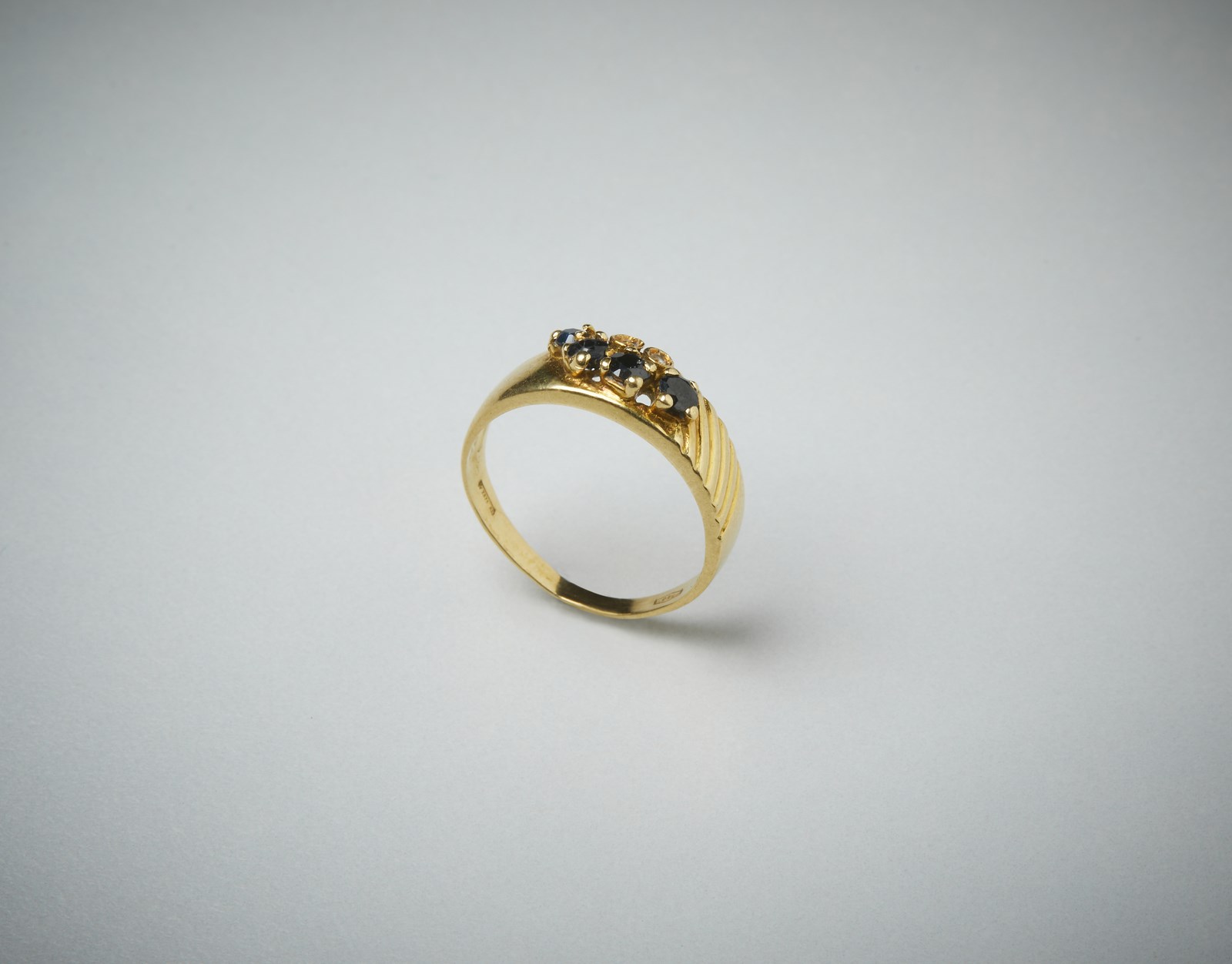 Anello in oro giallo 750/1000  a fascetta con piccoli quattro zaffiri blu di 0.35 ct. e due piccoli diamanti.  (. )