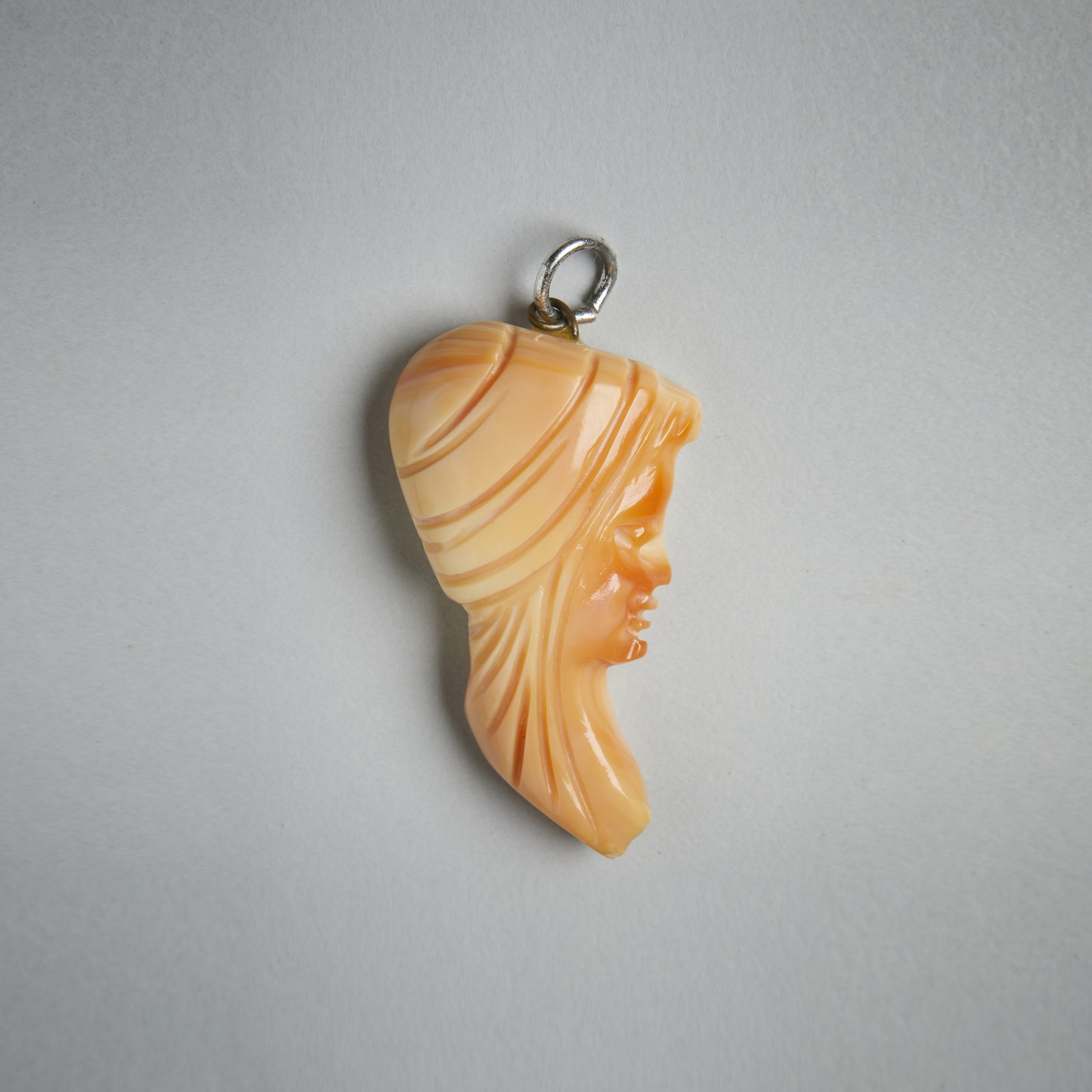Pendant with woman’s face in orange coral. (. )