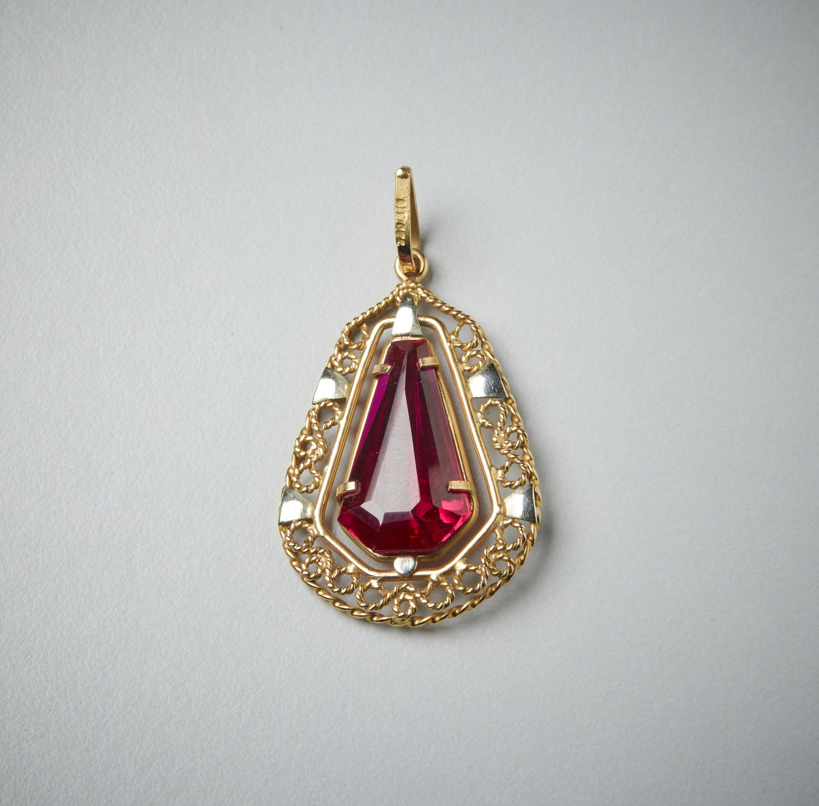 Pendant in yellow gold 750/1000 trapezioidal shape perforated with red synthetic stone.  (Milan Kicin)