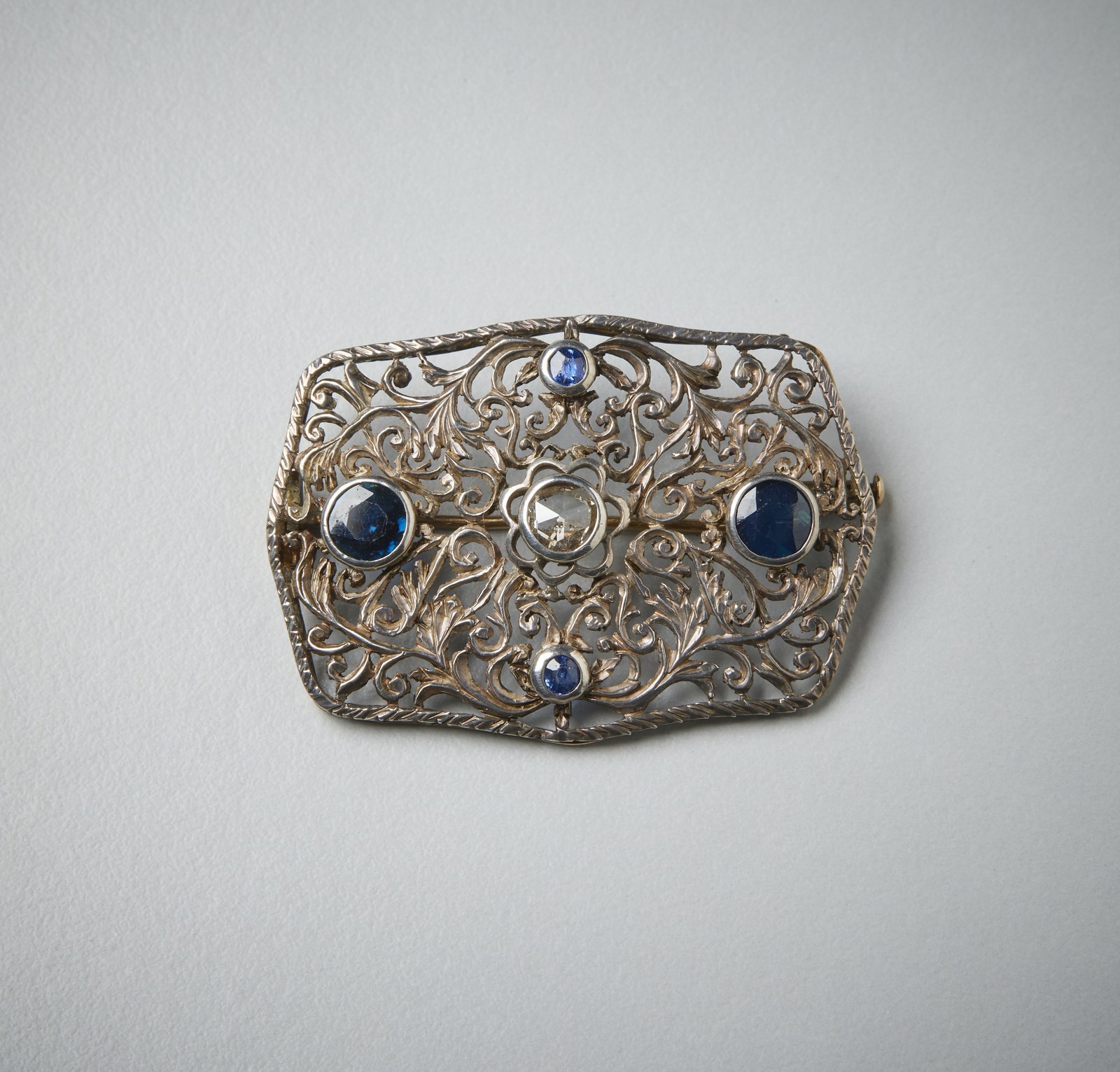 Rectangular openwork brooch with blue sapphires of approx 1.80 ct; central diamond rosette cut 0.35 ct approx. (. )