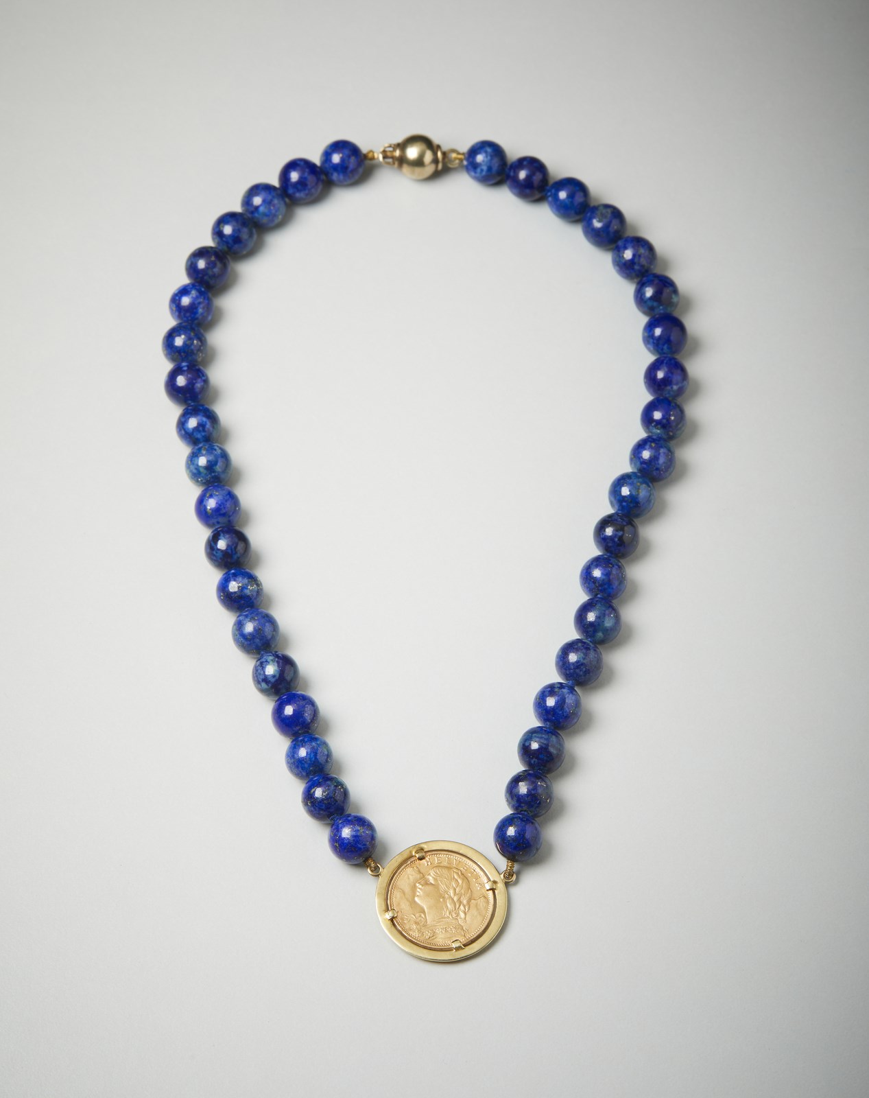 Lapis necklace with twenty Swiss francs in gold pendant.  (. )