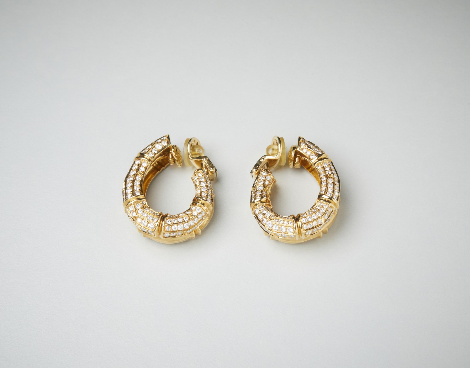 Paio di orecchini Cartier a clips doppio cerchio in oro giallo 750/1000 con pavè di diamanti bianchi di 4 ct circa. 
 ( Cartier)