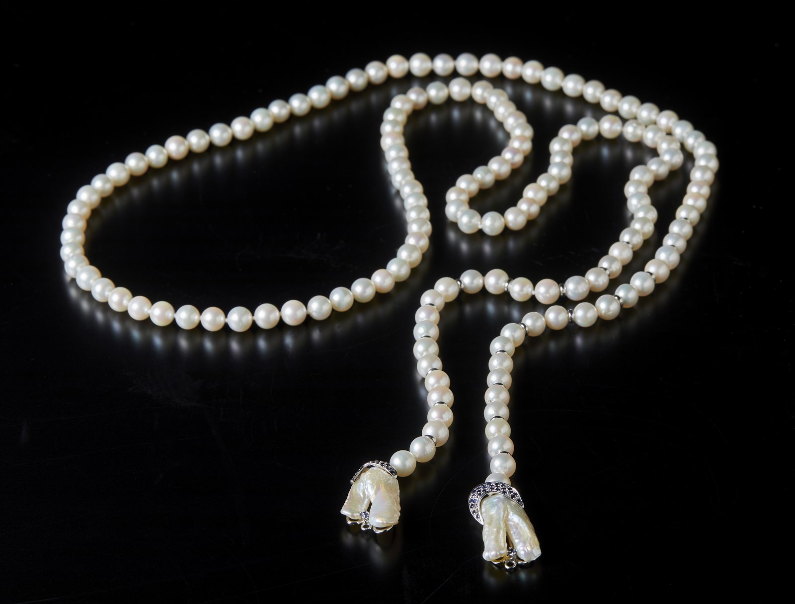 Collana di perle bianche coltivate in acqua saltata. 
Inserti  in oro bianco 750/1000 e terminali in madreperla con zaffiri blu di 1.20 ctt circa.
 (. )