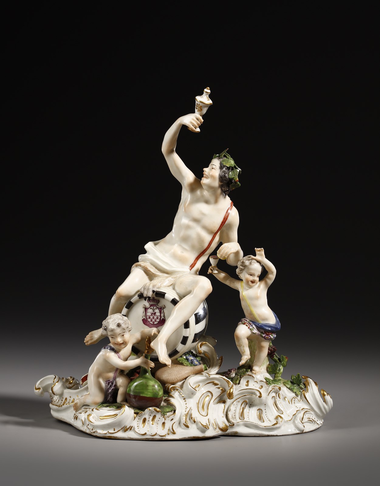 Gruppo in porcellana raffigurante Dioniso seduto su un otre di vino recante uno stemma e attorniato da due giovani satiri ( Manifattura Di Meissen Del XIX Secolo)