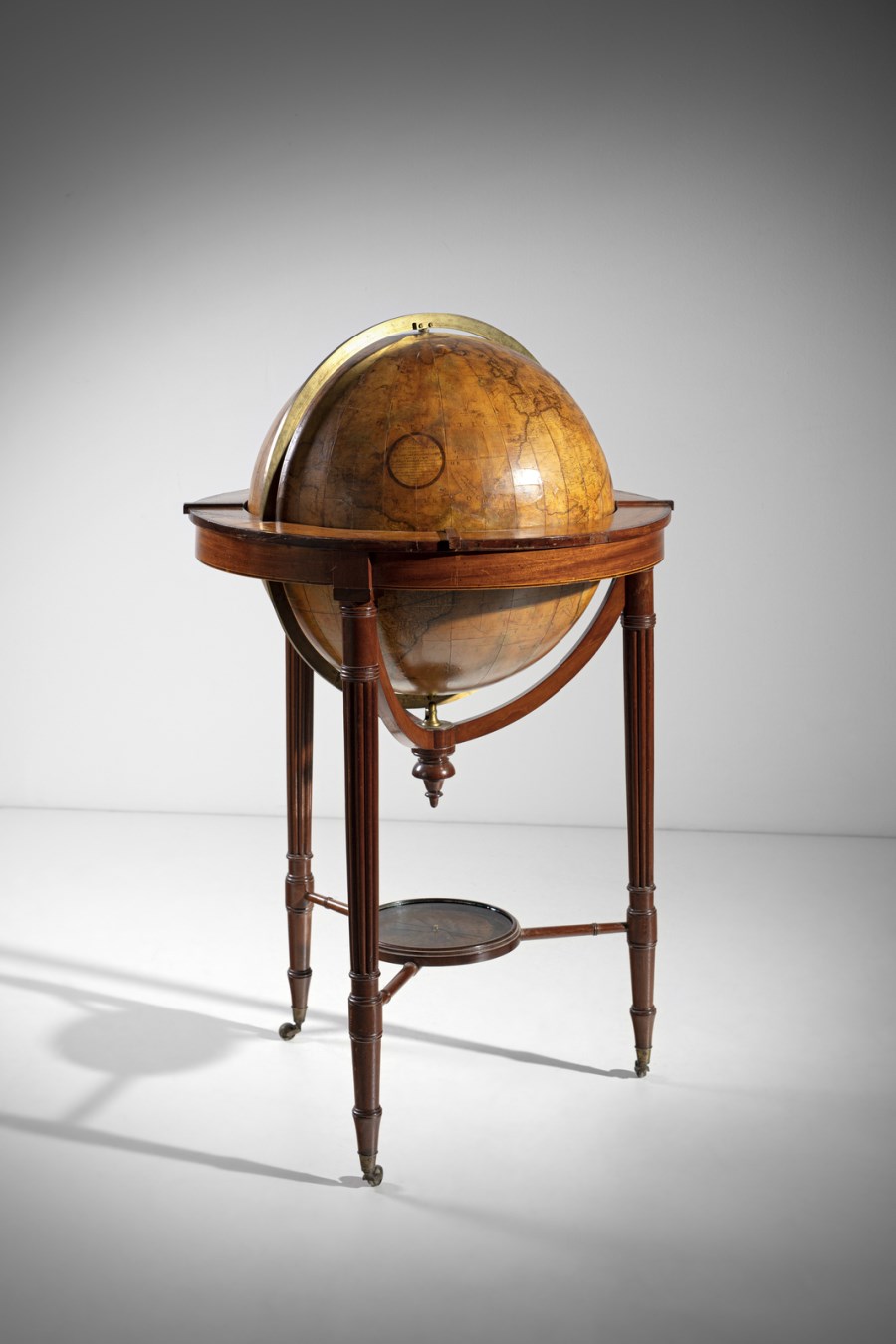 A Regency terrestrial globe raised on a mahogany stand on three circular reeded legs united by stretchers supporting a compass and terminating in brass castors ( John & William Cary, Londra, 1806)